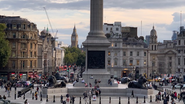 Trafalgar Square seen from the steps, with the column in the middle, the bronze lions and a clock tower in the distance.
