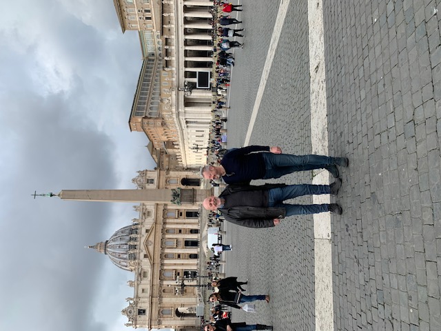 In St Peter's Square, with the basilica and the obelisk in the background under a cloudy sky.