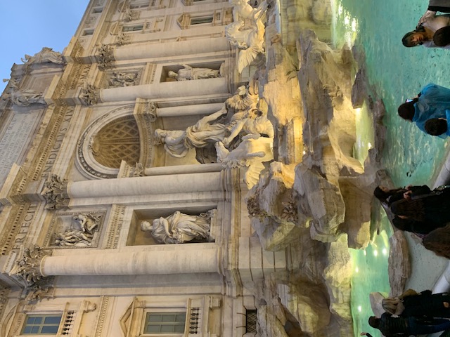 The Trevi Fountain bathes in warm light against the evening sky of Rome.