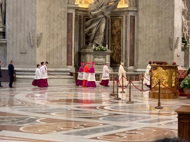 Clergy in procession over the marble floor of St Peter's Basilica.