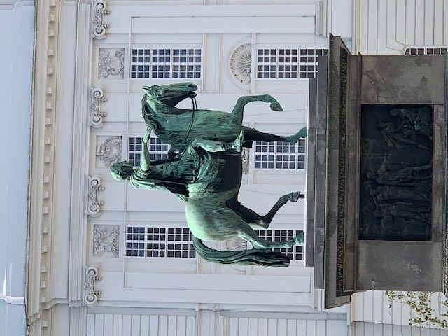 Bronze equestrian statue of Emperor Joseph II on a stone plinth in the Hofburg's Josefsplatz, pale palace façade behind.