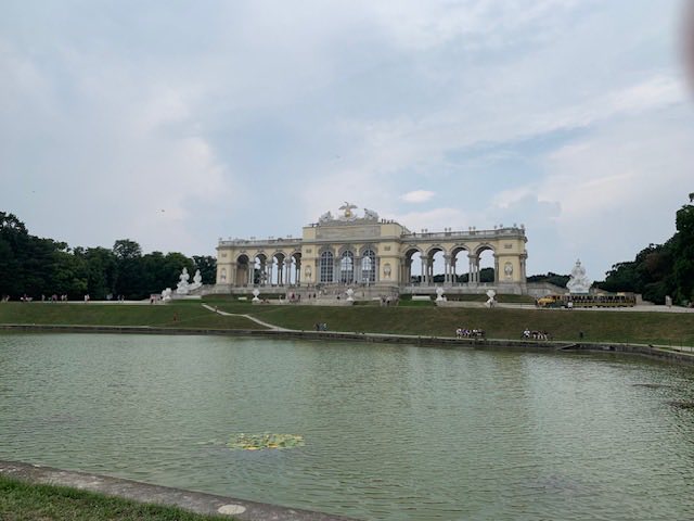 The Gloriette colonnade on the hill at Schönbrunn seen across the still water of the palace pond.