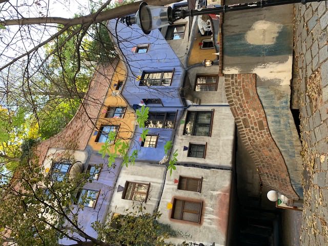 The same house in autumn, its blue and white walls behind bare branches and a street lamp.