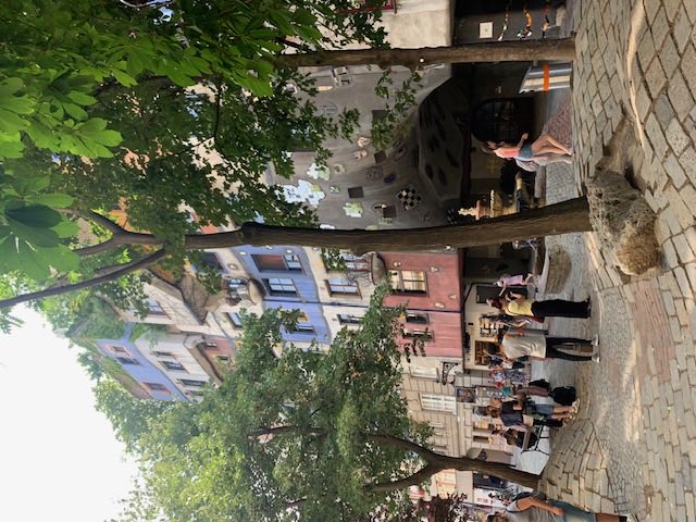 The cobbled square opposite the Hundertwasserhaus with young trees and a small tiled fountain.